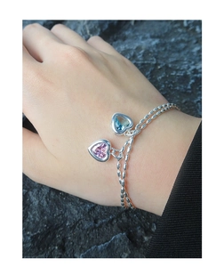 Detail view of double-layered beaded silver chain bracelet with pink and blue heart gems