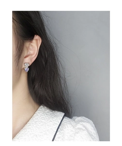 Macro view of S925 silver heart earrings with white and purple cubic zirconia stones