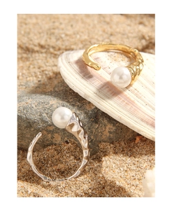 Detail of S925 silver pearl rings with crumpled texture on natural beach sand