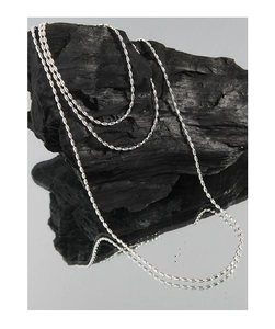 Macro d'un collier à billes en argent sterling S925 sur fond de charbon de bois texturé