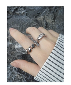 Detail showing an S925 silver twist ring and geometric zircon ring worn on a hand