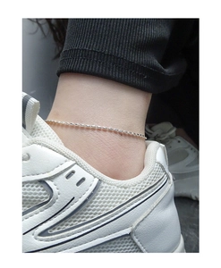 Gros plan sur une chevillère minimaliste en argent sterling S925 avec une texture fine
