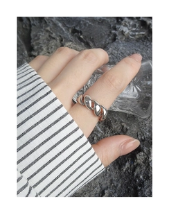 Close-up of twisted silver S925 ring texture worn against a modern backdrop