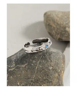 Macro shot of silver textured ring with colored cubic zirconia on natural stone
