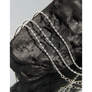 Collier minimaliste en argent sterling S925 présenté sur un support en pierre noire
