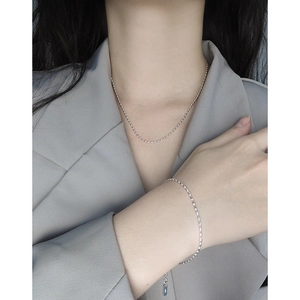 Ensemble collier et bracelet minimalistes en argent sterling S925 portés sur veste grise