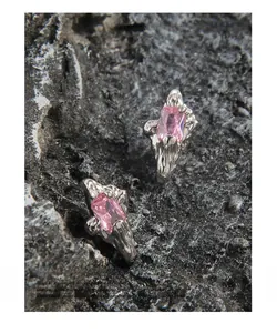 Macro view of irregular silver textured earrings with rectangular pink zircon stones