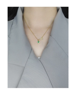 Detail of S925 silver necklace with green heart pin pendant on a gray blazer