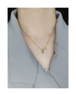 Detailed view of S925 silver safety pin necklace with green heart gem on a model