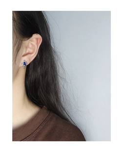 Macro shot of S925 silver earring with sapphire-blue gemstone and irregular texture