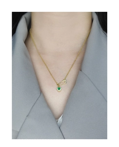 Detail of S925 silver necklace with golden safety pin and green heart zircon pendant