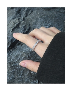 Close-up of S925 sterling silver gear ring with white zircon stones on a dark rock