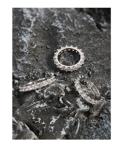 Detailed view of three S925 sterling silver gear rings with cubic zirconia on black rock