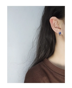 Detail of S925 silver stud earring with blue rectangular zircon on model's ear