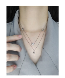 Close-up of a double-layered S925 silver necklace with floral and heart pendants