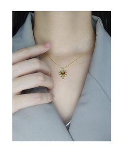 Detail of a gold heart pendant necklace with multi-color stones on a grey suit jacket