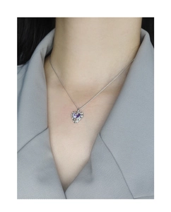 Detailed close-up of a silver heart necklace with a purple gemstone on a model's neck