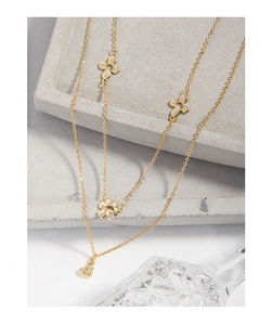 Close-up of a layered gold necklace featuring textured flower charms and a heart pendant