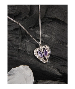 Detailed macro of heart pendant with purple stones on a dark textured background