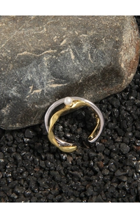 Close-up of dual-tone crossover ring with white pearl on minimalist stone background