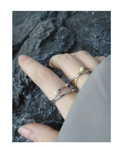 Close-up of minimalist double-layer cross rings in gold and silver with small white pearls