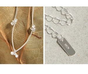 Macro detail of S925 sterling silver chain link with authentic hallmark tag and beads