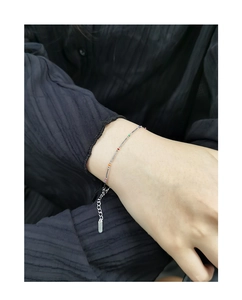Macro shot of silver bamboo chain bracelet with colorful beads on a female wrist
