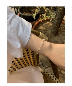 Close-up of a minimalist silver segmented chain bracelet on a model's wrist outdoors