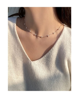 Close-up of minimalist S925 sterling silver beaded bar necklace on model's neck
