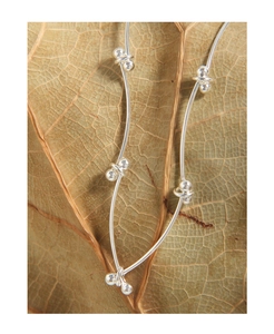 Macro shot of S925 sterling silver beaded chain necklace resting on a natural brown leaf
