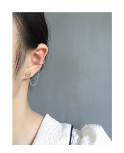 Detail of amber crystal stud and textured silver ear cuff linked by fine chain
