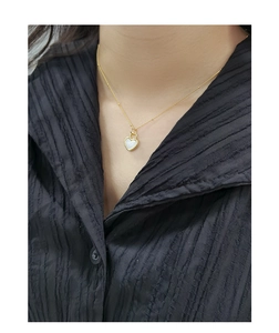Gros plan d'un collier avec pendentif cœur en nacre blanche porté par un mannequin
