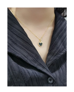 Gros plan d'un collier cœur doré avec incrustation d'agate noire sur un mannequin