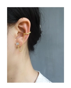 Detail of gold chain earring set with rectangular zircon and twisted ear cuff on ear