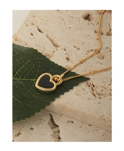 Détail du collier cœur en agate noire avec chaîne perlée dorée et bordure texturée