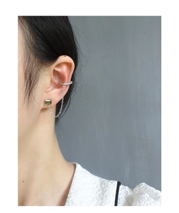 Detail of S925 silver ear cuff and emerald zircon stud linked by delicate chain