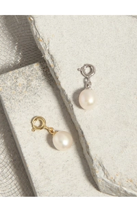Dettaglio di chiusure in argento S925 e oro con perle naturali su sfondo a maglia moderno