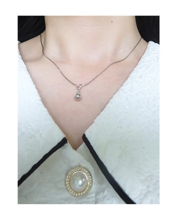 Dettaglio di un ciondolo a sfera in argento sterling S925 minimalista su catena fine