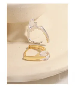Macro detail of U-shaped silver earrings with large round zircon on ceramic base