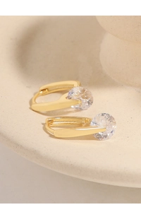 Macro detail of U-shaped gold earrings featuring round cubic zirconia in a minimalist style