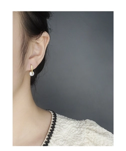 Close-up of elegant gold U-shaped earrings with brilliant round zircon on model