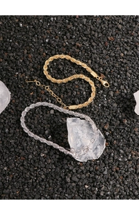 Close-up of gold and silver rope chain bracelets on dark stones with crystal detail