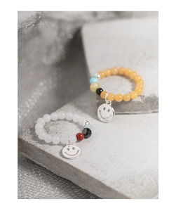 Dettaglio del ciondolo smiley in argento S925 su anelli elastici di perle colorate