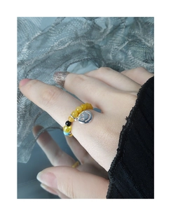 Dettaglio dell'anello elastico con perline gialle e ciondolo smiley in argento