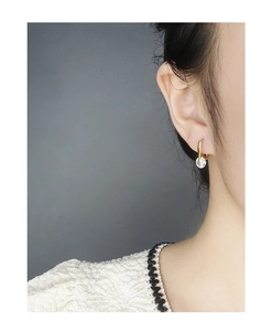 Close-up of minimalist gold geometric U-shaped earrings with round zircon on a model