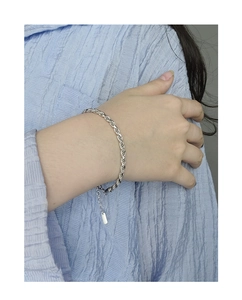 Macro shot of a silver twisted rope bracelet on a wrist with adjustable chain and tag