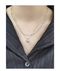 Detail view of double-layer silver necklace featuring colorful beads and a heart pendant