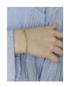 Detail of a 18k gold twisted rope chain bracelet with polished finish on wrist