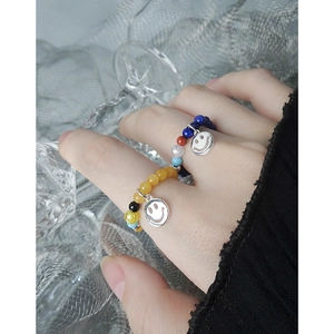 Anelli elastici con perline minimalisti e ciondoli a faccina d'argento sulla mano