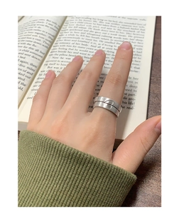 Détail de bagues de couple cœur en argent mat sur fond de livre au style minimaliste